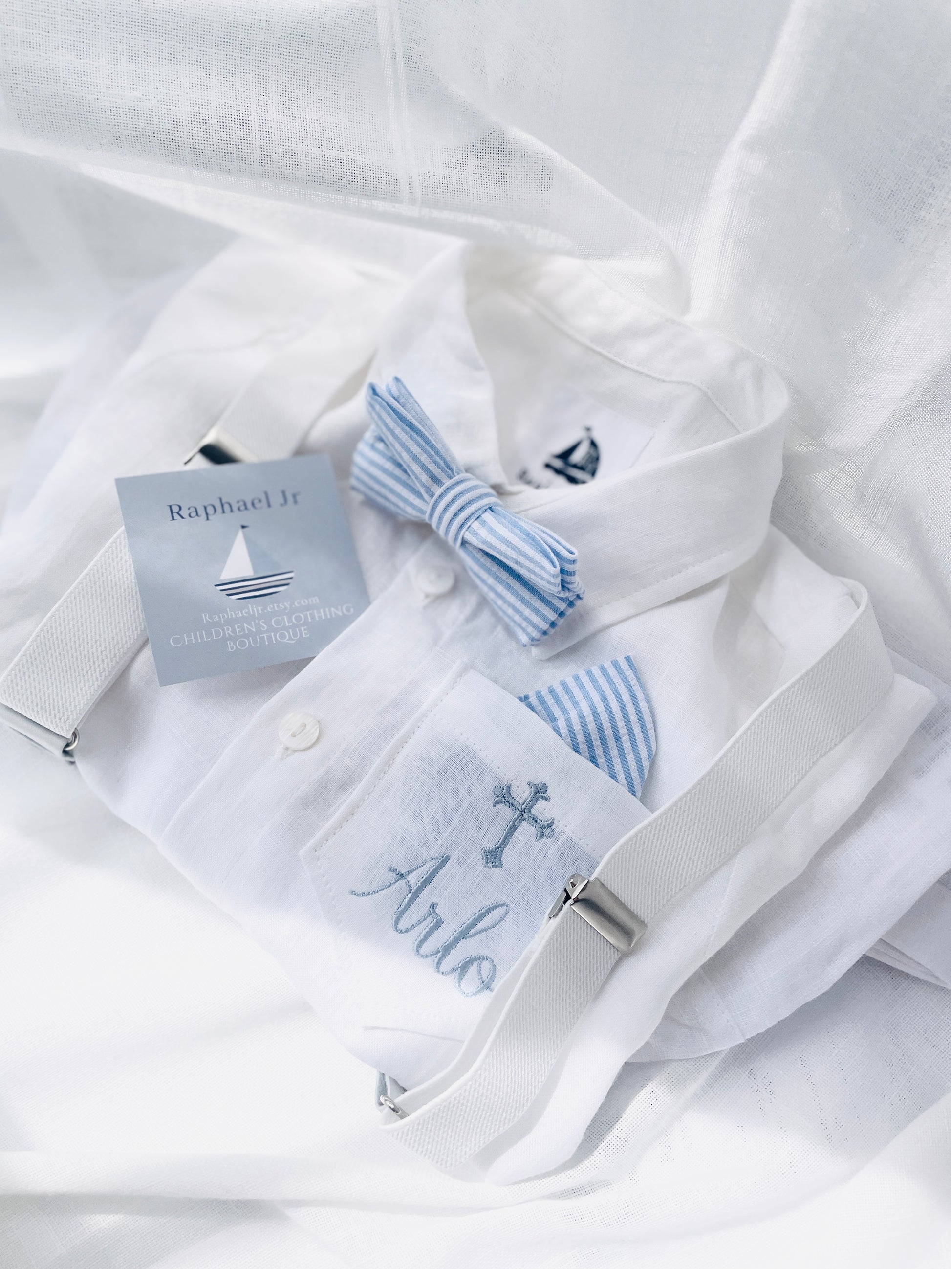 Arlo in dusty blue font Haydena and ornate cross above and the stripey blue bowtie and pocke square