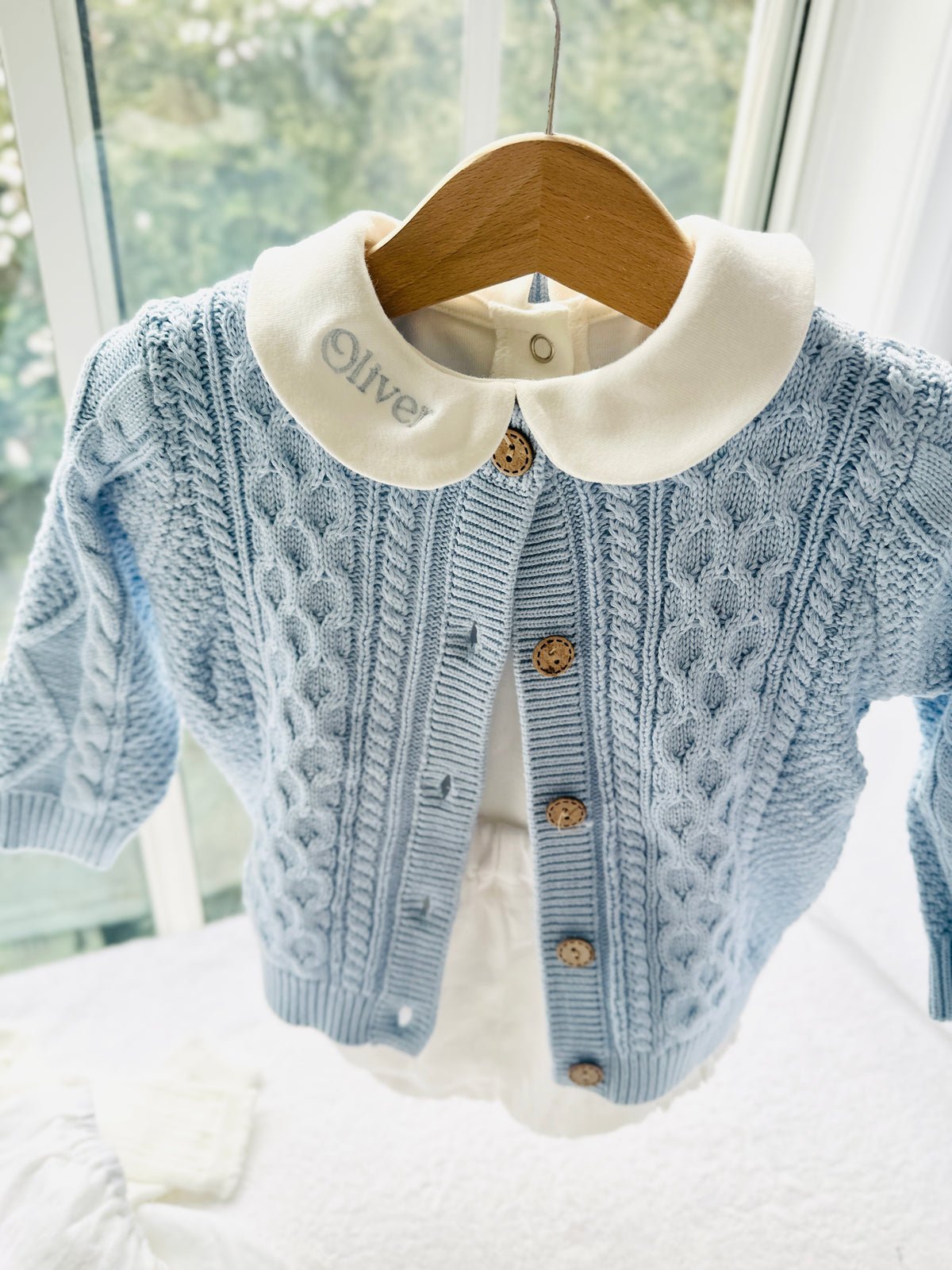 Baby outfit with blue cardigan, round collar bodysuit and white linen bloomers and long socks
