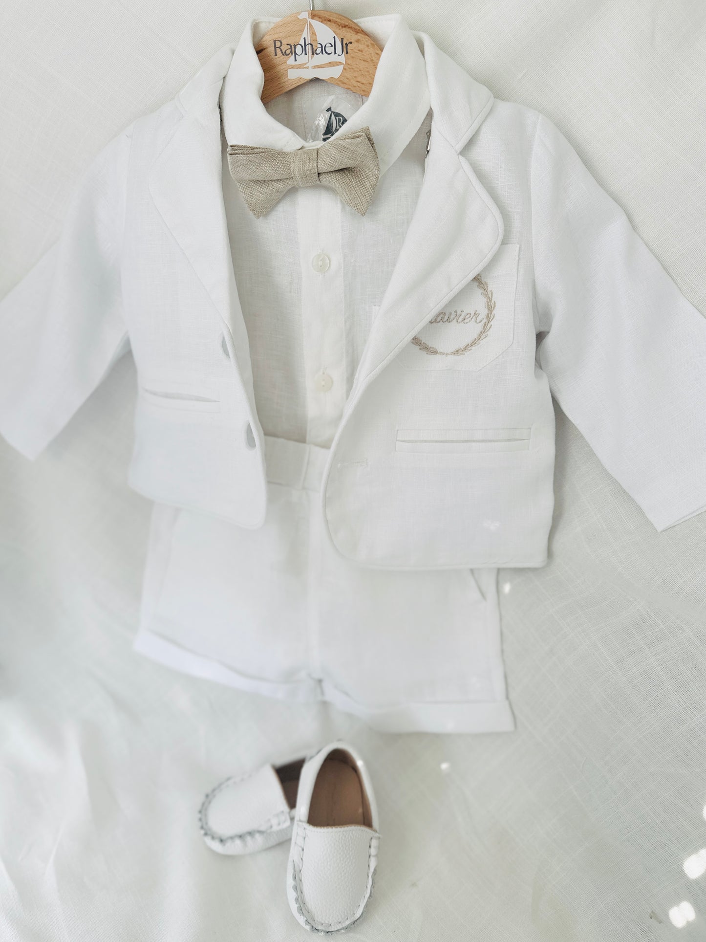 White linen shirt and shorts and jacket Baptism suit with a beige bowtie and beige embroidered pocket and white suspenders
for a baby boy with leather loafers by Raphael Jr 