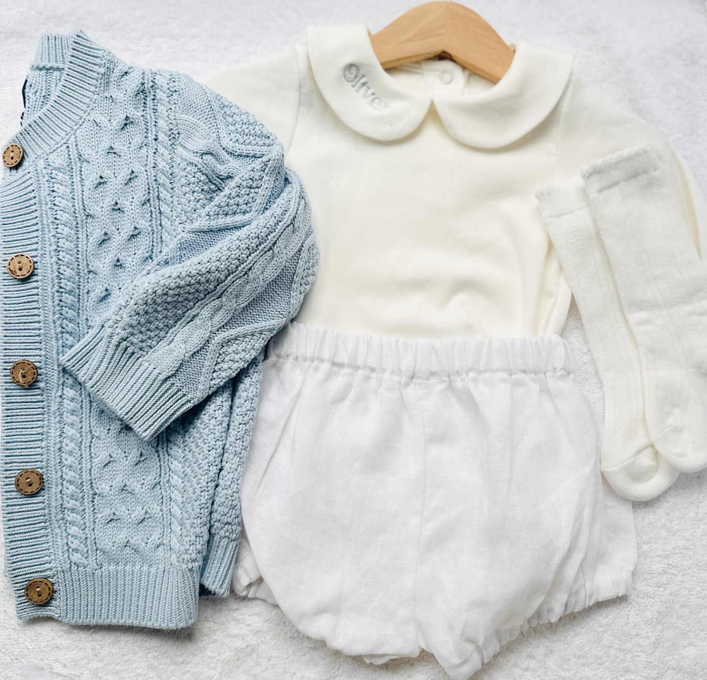 Baby outfit with blue cardigan, round collar bodysuit and white linen bloomers and long socks