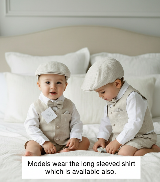 Two babies in matching beige linen vests and shorts outfits sitting on a bed.