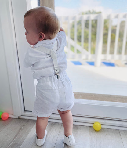 White linen shirt and shorts Baptism suit with a beige bowtie and white suspenders
for a baby boy with leather booties by Raphael Jr 